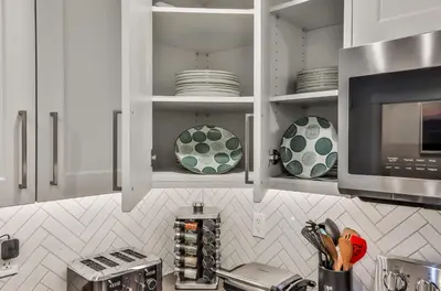 a kitchen with white cabinets and plates and a microwave at The Parq by Samsara Resort Top View Downtown 4BR & 3BTH in Canmore