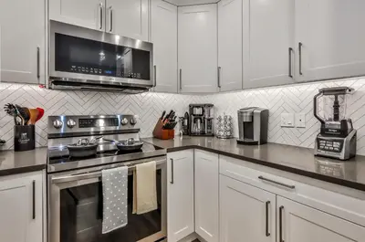 a kitchen with white cabinets and a stove top oven at The Parq by Samsara Resort Top View Downtown 4BR & 3BTH in Canmore