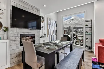 a dining room with a table and a fireplace at The Parq by Samsara Resort Top View Downtown 4BR & 3BTH in Canmore
