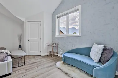a living room with a blue couch and a window at The Alpine Escape by Samsara Resort Top View Downtown 4BR & 3BTH in Canmore