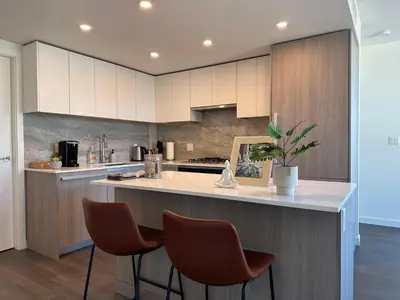 a kitchen with white cabinets and a counter with chairs at UBC Pacific Spirit Modern Style Home in Vancouver