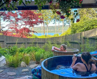 two women sitting in a hot tub in a garden at Manna House in Denman Island