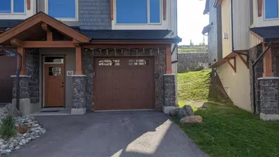 a house with a wooden garage door and a driveway at Echo Landing #42 by Bear Country in Sun Peaks