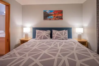 a bedroom with a large bed with two lamps at Top Floor Condo - 2BR & AC with Mountain Views in Canmore