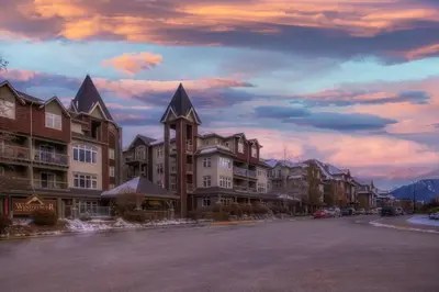 a group of buildings on a street at sunset at Top Floor Condo - 2BR & AC with Mountain Views in Canmore