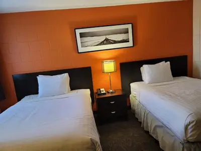 two beds in a hotel room with orange walls at Roadking Inns Motel in Calgary