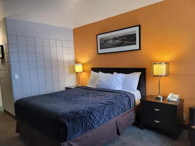 a hotel room with a bed with two lamps and a phone at Roadking Inns Motel in Calgary