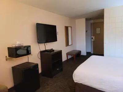 a hotel room with a bed and a flat screen tv at Roadking Inns Motel in Calgary