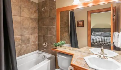 a bathroom with a tub and a toilet and a sink at I Spy - Cozy Pet Friendly, Ski In Ski Out Condo with Private Hot Tub in Big White