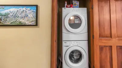 a washer and dryer in a room next to a door at I Spy - Cozy Pet Friendly, Ski In Ski Out Condo with Private Hot Tub in Big White