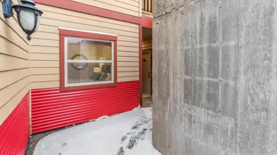 a red wall on the side of a building with a window at I Spy - Cozy Pet Friendly, Ski In Ski Out Condo with Private Hot Tub in Big White