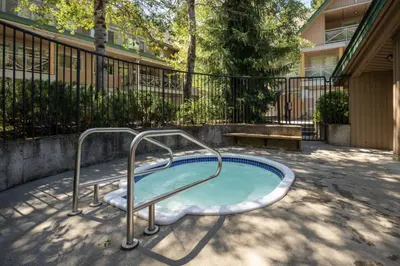 a hot tub with a metal rail in a yard at 3BR in Valhalla, Village Location, Communal Hot Tub, Gas Fireplace, Parking in Whistler