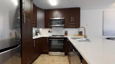 a kitchen with wooden cabinets and a stove top oven at 1BR and Den in Marketplace Lodge, Gas Fireplace, Village Location, Complex Hot Tub in Whistler