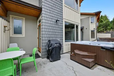 a patio with a table and chairs and a trash bag at Spacious Modern Ski-in Ski-out with Hot Tub Townhouse in Sun Peaks