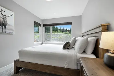 a white bedroom with a bed and a window at Spacious Modern Ski-in Ski-out with Hot Tub Townhouse in Sun Peaks