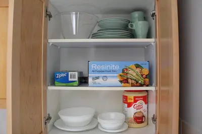 a cupboard filled with dishes and other kitchen items at Windtower Lodge - Canmore in Canmore