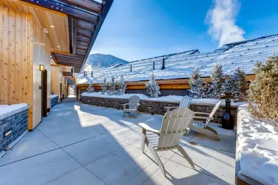 a patio with two chairs and a table with snow on it at Peaks Hotel and Suites in Banff