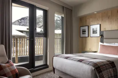 a bedroom with a bed and a window with a balcony at Peaks Hotel and Suites in Banff