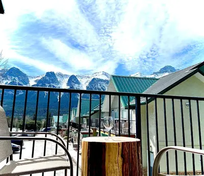 a glass of wine on a table on a balcony with mountains at MountainView -PrivateChalet Sleep7- 5min to DT Vacation Home in Canmore