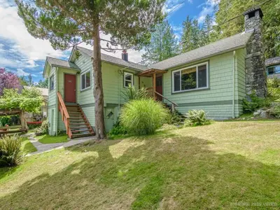 a green house with a tree in the yard at Woods End Landing in Bamfield