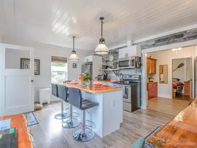 a kitchen with white cabinets and a island with bar stools at Woods End Landing in Bamfield