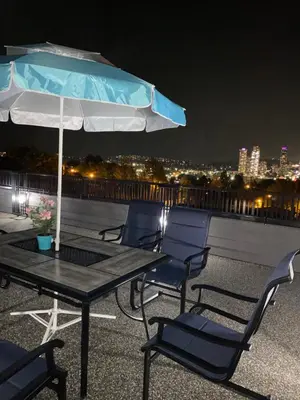 a table and chairs with an umbrella on a roof at Six minutes to Rupert station in Vancouver