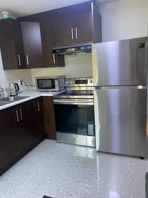 a kitchen with stainless steel appliances and wooden cabinets at Six minutes to Rupert station in Vancouver