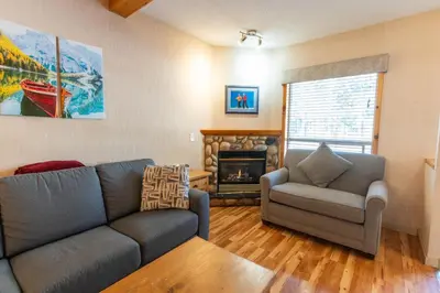 a living room with a couch and a chair and a fireplace at BANFF WOODS LODGE in Canmore