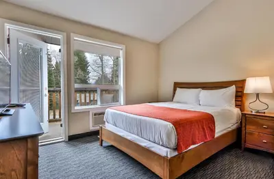 a bedroom with a bed and two windows and a desk at BANFF WOODS LODGE in Canmore