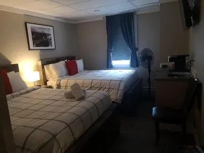 a bedroom with two beds and a desk and a fan at The Cache Hotel and Lodgings in Golden