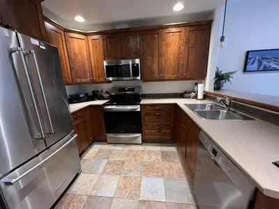 a kitchen with wooden cabinets and stainless steel appliances at Trappers Landing #34 by Bear Country in Sun Peaks