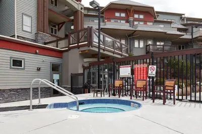 a swimming pool with chairs and a building at Newly Renovated Grizzly Lodge, Spacious 3BR 2BA with open pool, hot tub in Canmore