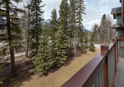 a balcony of a house with a view of trees at Newly Renovated Grizzly Lodge, Spacious 3BR 2BA with open pool, hot tub in Canmore