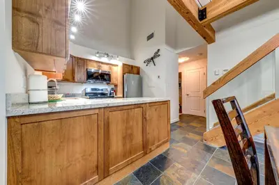 a kitchen with wooden cabinets and a counter top at Greystone Lodge 413 - Largest in Whistler