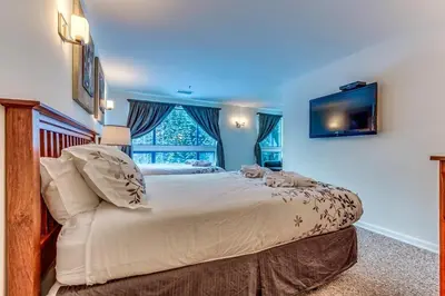 a bedroom with a large bed and a window at Greystone Lodge 413 - Largest in Whistler