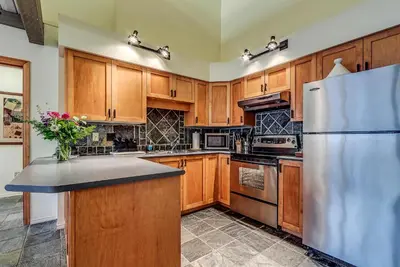 a kitchen with wooden cabinets and a refrigerator at Greystone Lodge 401 Ski-in Out in Whistler