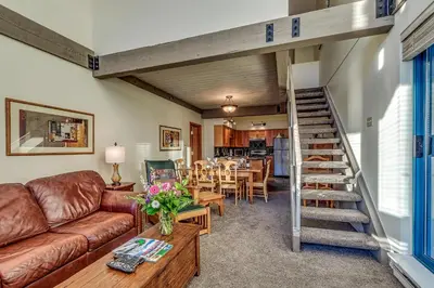a living room with a couch and a staircase at Greystone Lodge 401 Ski-in Out in Whistler