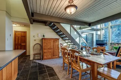 a kitchen and dining room with a wooden table and chairs at Greystone Lodge 401 Ski-in Out in Whistler