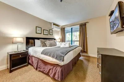 a bedroom with a large bed and a television at Greystone Lodge 408 Luxury in Whistler
