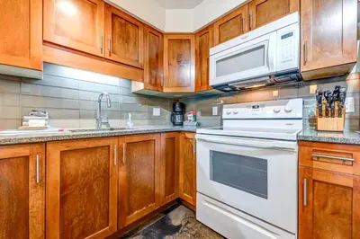 a kitchen with wooden cabinets and white appliances at Greystone Lodge 226 Ski-in Out in Whistler