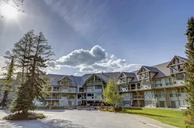 a large apartment building with a tree in the foreground at Greystone Lodge 226 Ski-in Out in Whistler