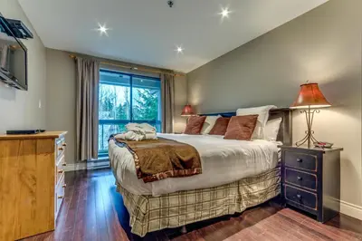 a bedroom with a large bed and a window at Greystone Lodge 216 Ski-in Out in Whistler