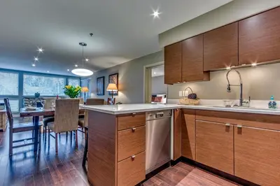 a kitchen with wooden cabinets and a dining room at Greystone Lodge 216 Ski-in Out in Whistler