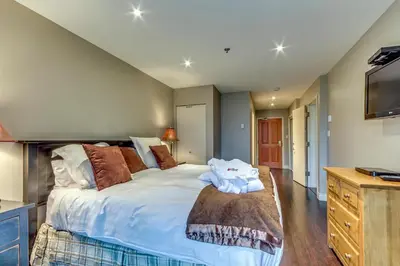 a bedroom with a large bed and a television at Greystone Lodge 216 Ski-in Out in Whistler