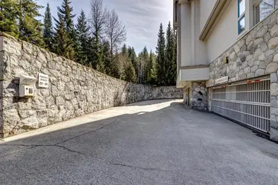 a stone wall next to a building with a garage at Greystone Lodge 221 Ski-in Out in Whistler