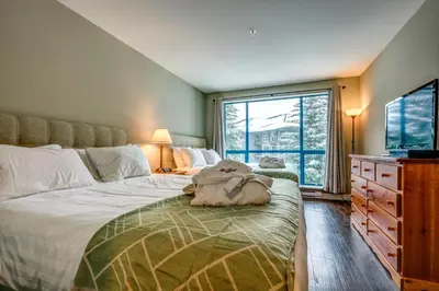 a bedroom with a large bed and a large window at Greystone Lodge 221 Ski-in Out in Whistler