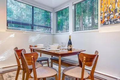 a dining room with a table and chairs and windows at Greystone Lodge 113 Ski-in Out in Whistler