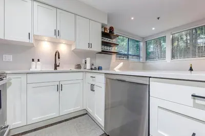 a white kitchen with white cabinets and a window at Greystone Lodge 113 Ski-in Out in Whistler