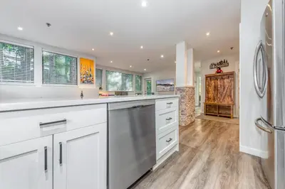 a large kitchen with white cabinets and a refrigerator at Greystone Lodge 113 Ski-in Out in Whistler