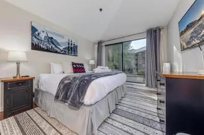 a bedroom with a bed and a large window at Greystone Lodge 113 Ski-in Out in Whistler
